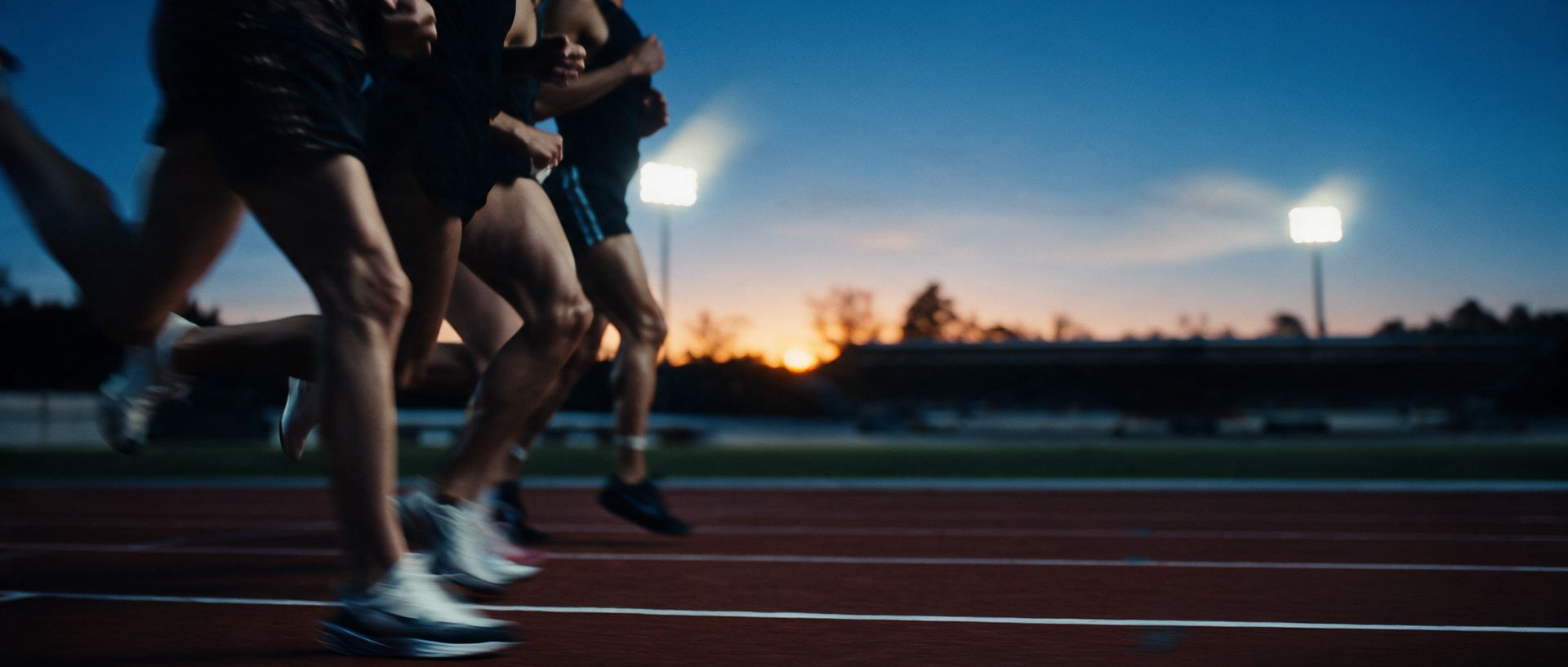 Runners striding in step on a track at dusk